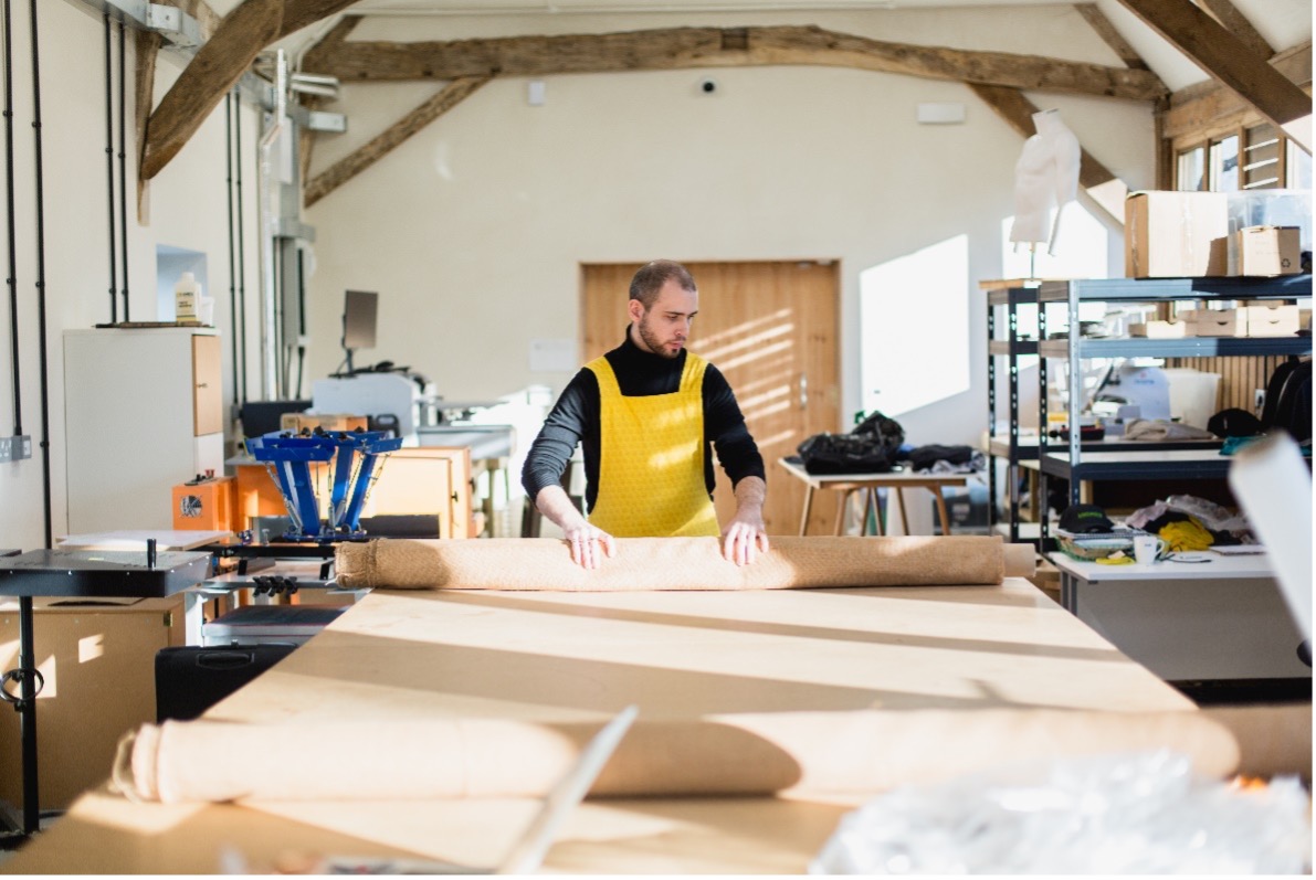 A member of the team at Doc Cotton working with a roll of fabric