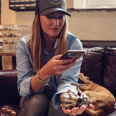 A woman using her mobile to take a photo of fishing equipment in her hand